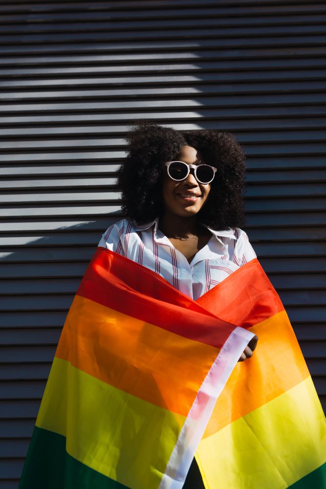 Smiling Black woman posing happily with the LGBT flag
