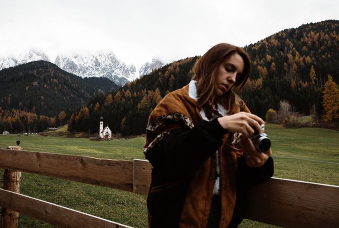 Woman with camera standing near church in mountains