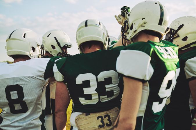 Rearshot of a football team huddling before a game