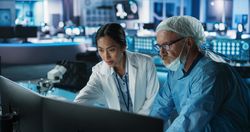 Medical Hospital Research Laboratory Meeting: Female Asian Neuroscientist Talking To Male Neurosurgeon About CT Brain Scans On TV Display.