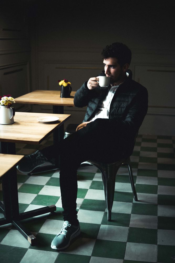 Man sitting on chair drinking from light cup