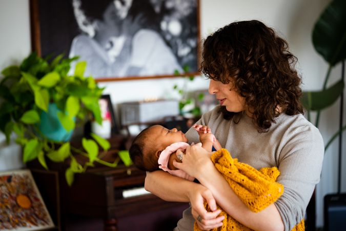 Woman holding newborn baby in her arms in her living room