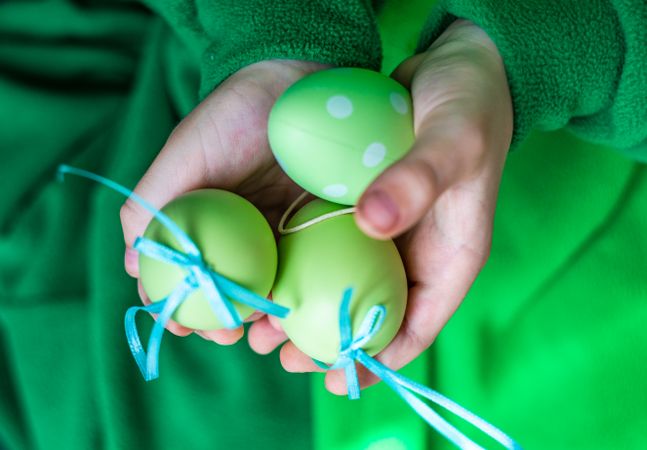 Person's hands holding green decorative eggs
