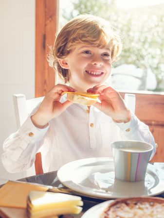 Happy kid eating delicious sandwich