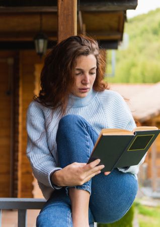Woman reading book on terrace of house
