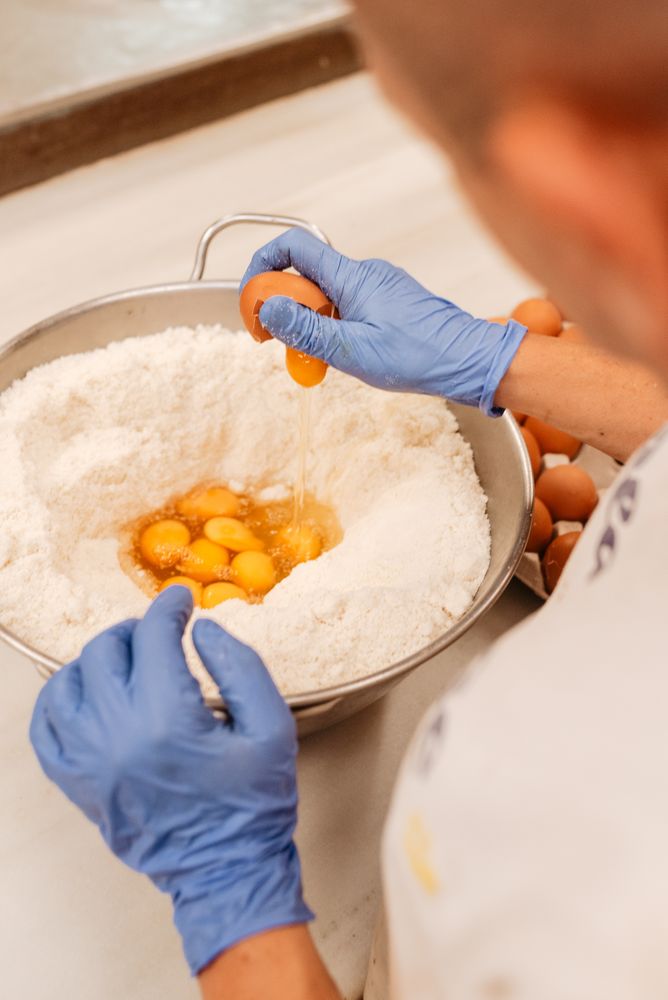 Crop cook breaking eggs into flour
