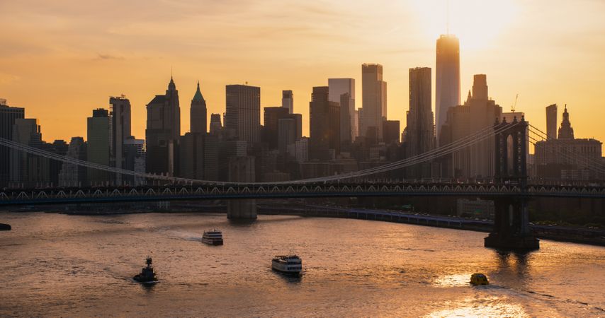 New York City Skyline Aerial Shot from a Helicopter at Sunset. Famous Skyscraper Buildings with Manhattan and Brooklyn Bridges. Busy Diverse Megapolis with Cars, Boats and People Moving Around