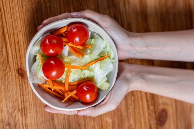 Hands holding a fresh salad bowl for healthy eating and wellness