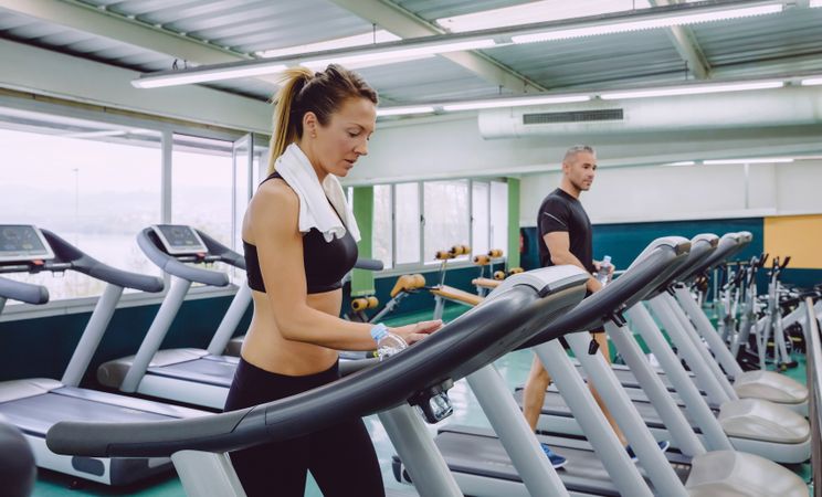Man and woman doing cardio on treadmills in gym