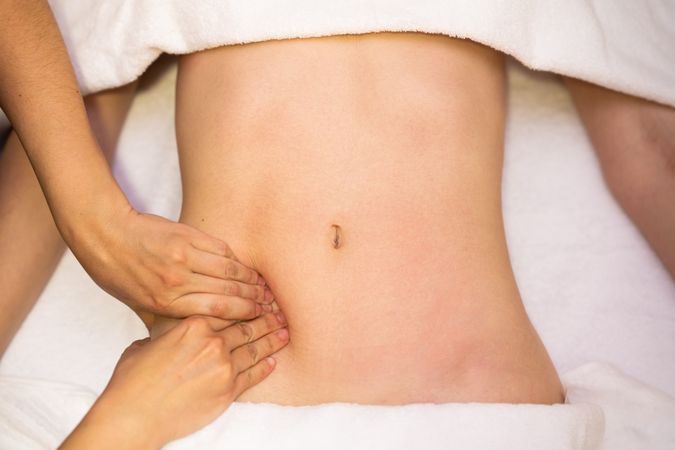 Top view of hands massaging a woman’s abdomen