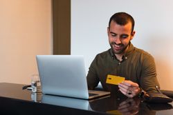 Cheerful man with credit card shopping online