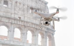 Unmanned Aircraft System Quadcopter Drone UAV In The Air Near The Colosseum In Rome.