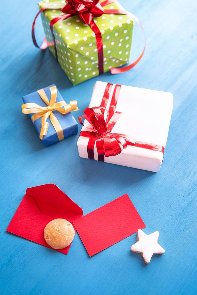 Top view of colorful presents and red envelope on blue table