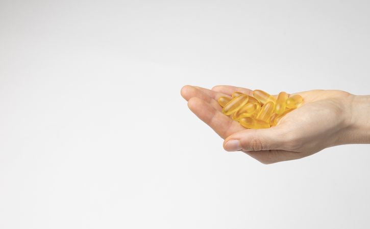 The hand of a woman holds a handful of oil capsules with omega 3, food supplement