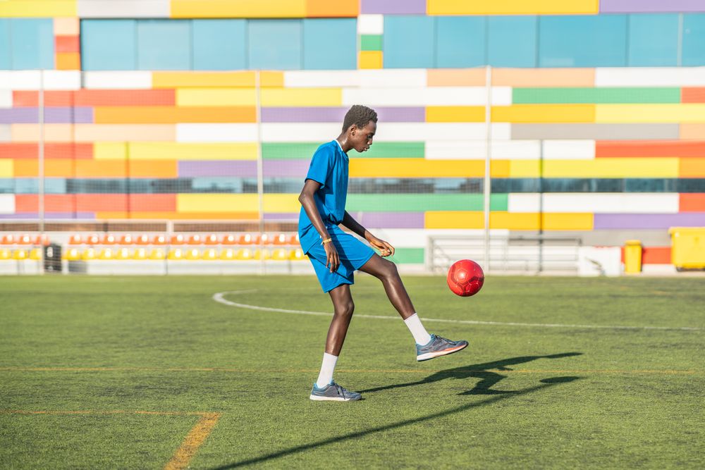 Black teenager juggling football ball