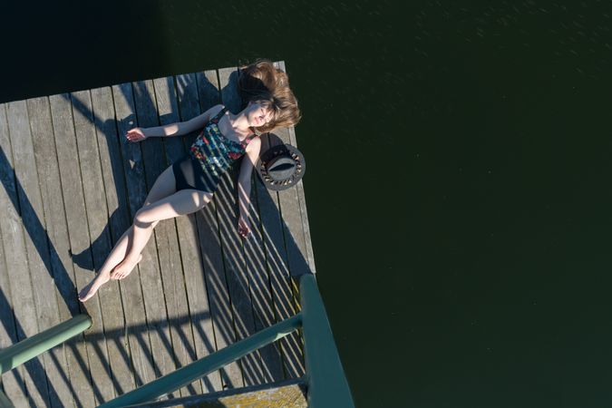 Young female lying down on pier on nature