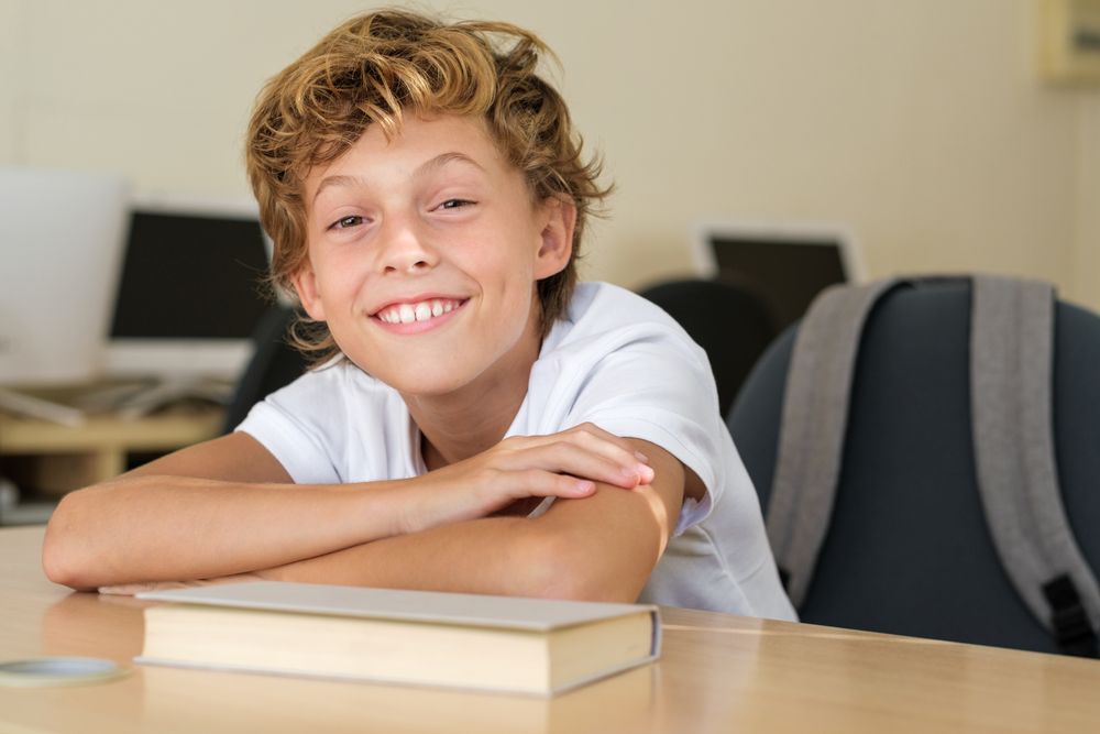Smiling schoolkid sitting at table in classroom