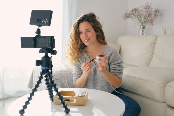 Female beauty blogger shooting video on camera at home