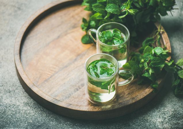 Mint tea with fresh mint leaves on wooden tray, with copy space