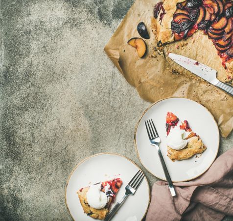 Two plates of fruit tart with whipped cream, with parchment paper, knife, square crop and copy space