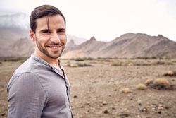 Positive man standing in mountainous area in cloudy day
