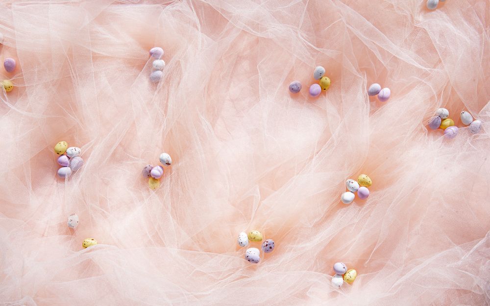 Easter mini eggs scattered on pink background