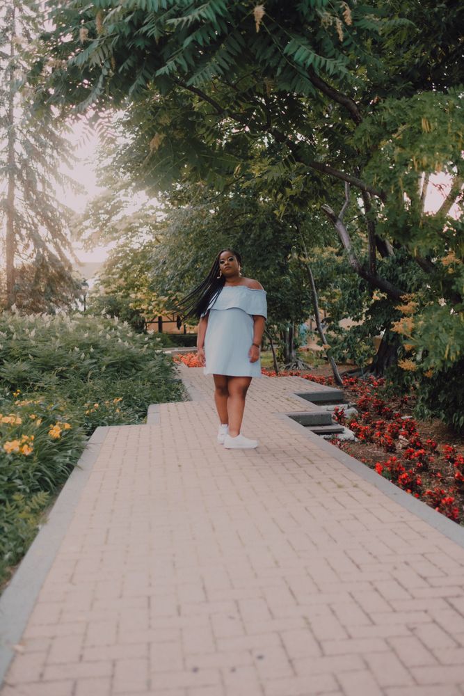 Confident Black woman walking along blossoming garden