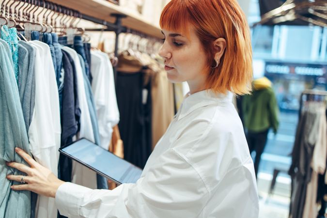 Businesswoman working in clothing store taking stock of clothes