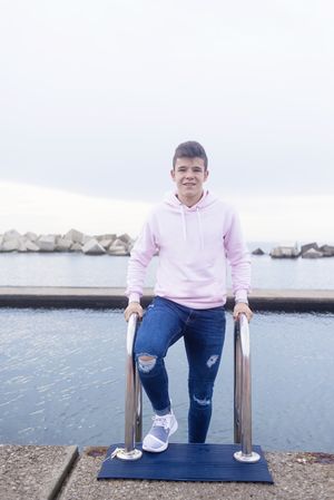 Young male teenager standing on promenade while looking at camera