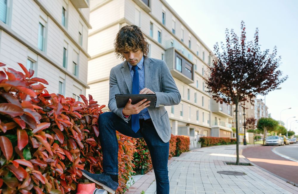 Businessman working with the tablet in the street