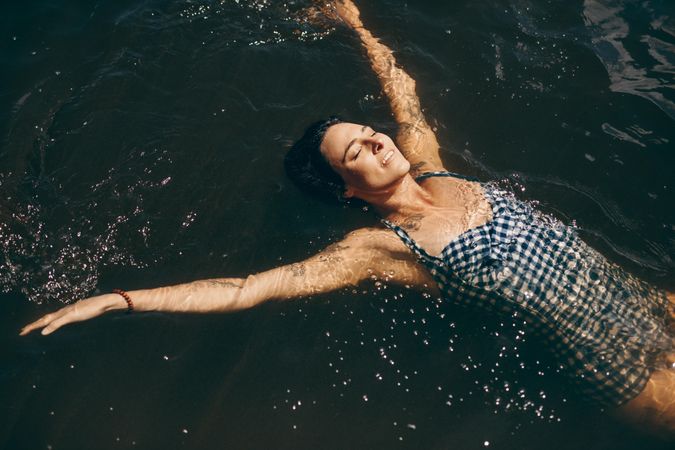 Woman in bikini swimming in lake on a sunny day