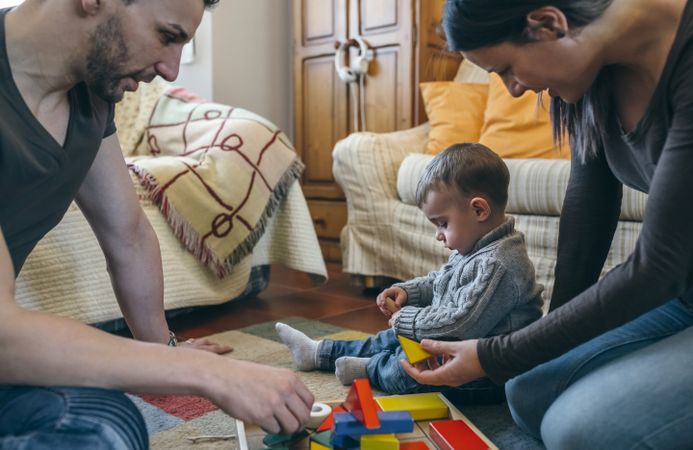 Parents playing with toddler a wooden game building