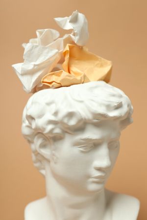 Marble bust with crumpled paper on brown background, vertical close up