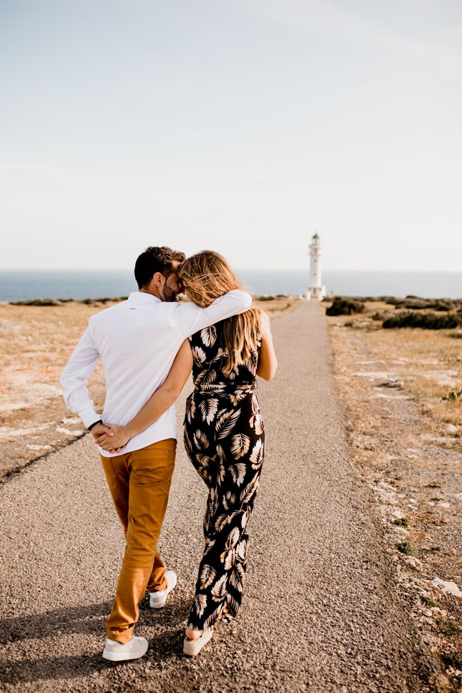 Smiling lovers cuddling on path to sea