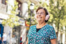 Mature woman walking down the street listening to music