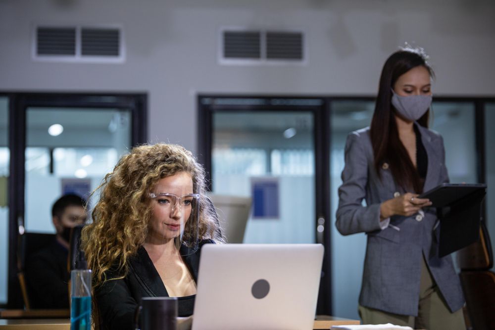 Colleagues in office wearing protective mask and face shield in office