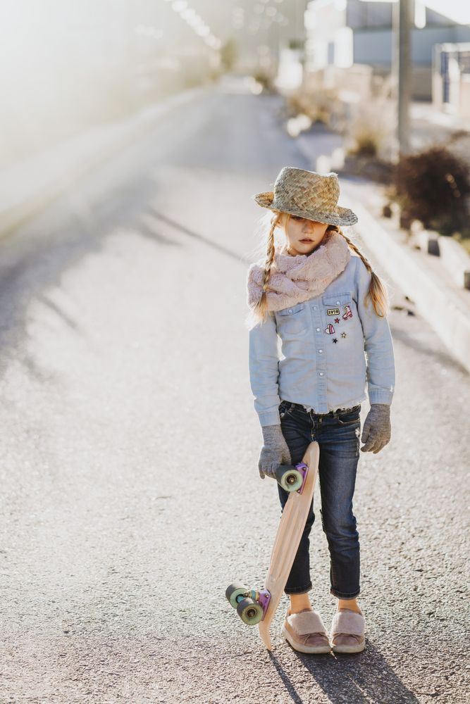 Stylish girl with skateboard on street