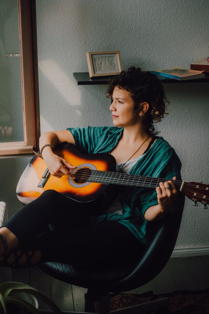 Content woman playing guitar at home