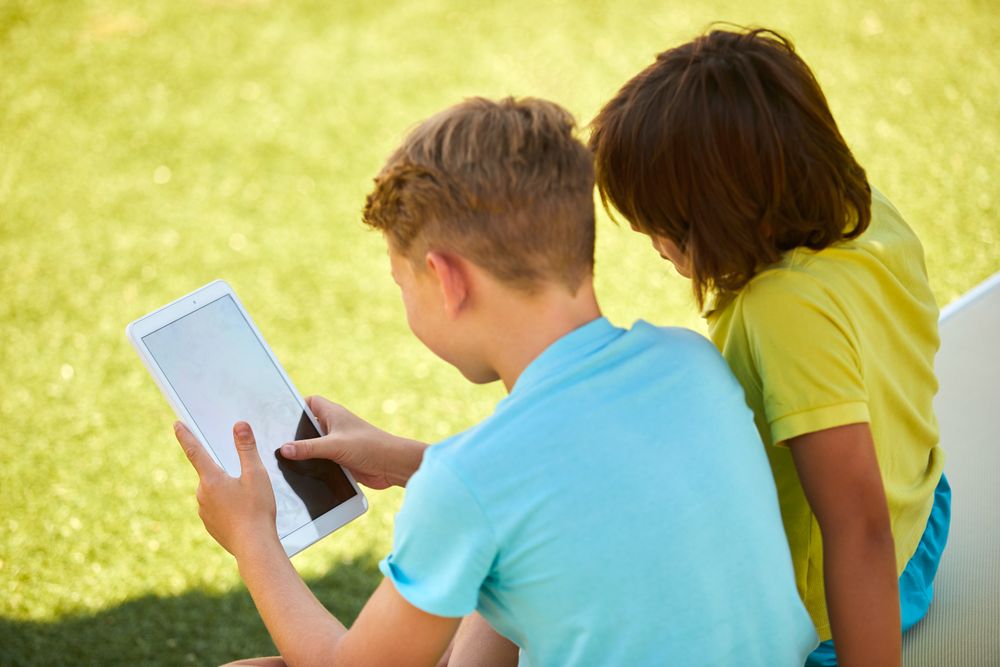 Boys using tablet in garden