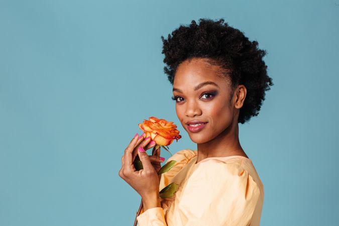 Studio shot of a content Black woman with a vibrant colored rose