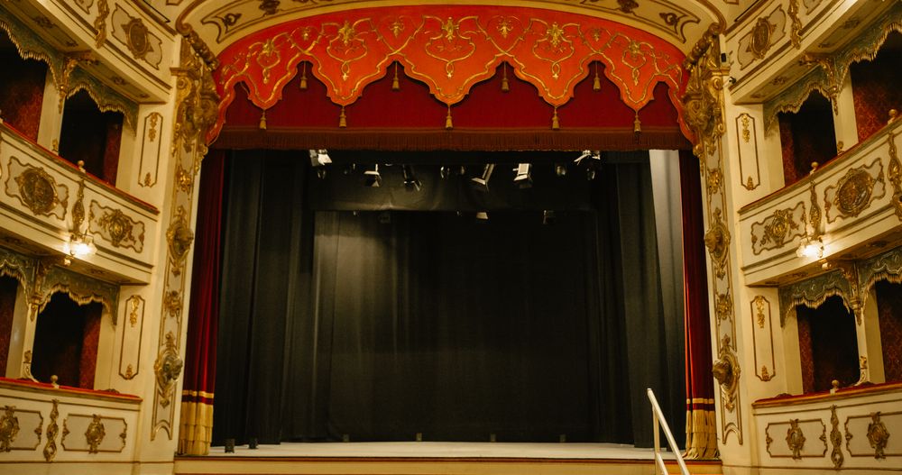 Wide shot of an Empty Elegant Classic Theatre with Big Stage and Red Velvet Curtains.