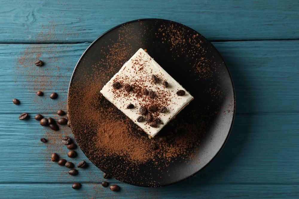 Plate with tiramisu on wooden background. Tasty dessert
