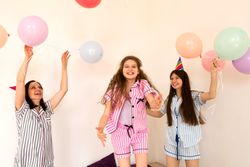 Joyful family in party hats playing with balloons indoors.