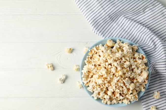 Flat lay composition. Towel and plate with popcorn on wood background