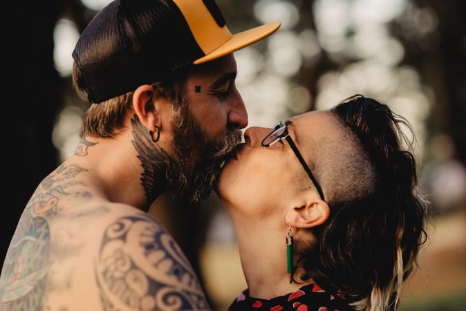 Happy couple hugging and kissing near tree in park