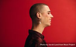 Profile view of man wearing an earring and makeup smiling 4jQdx5
