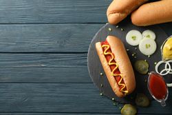 Tasty hot dog and ingredients on wooden background