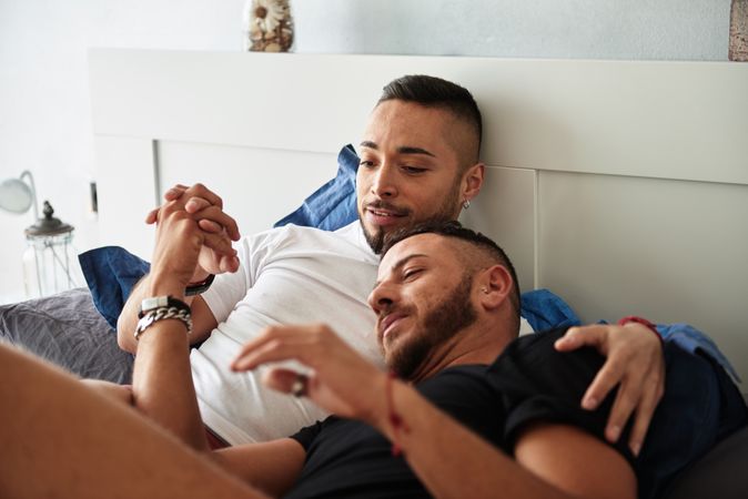 Smiling gay couple hugging on bed