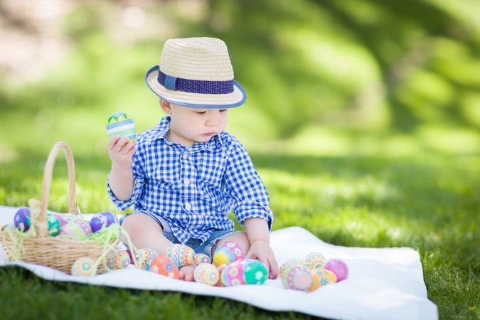 Biracial Child Outside Wearing Rabbit Ears Playing with Easter Eggs