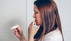 Pregnant looking at a pregnancy test